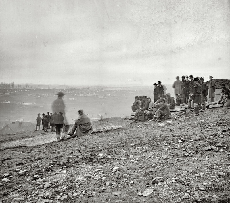 Men on a hillside overlooking a city