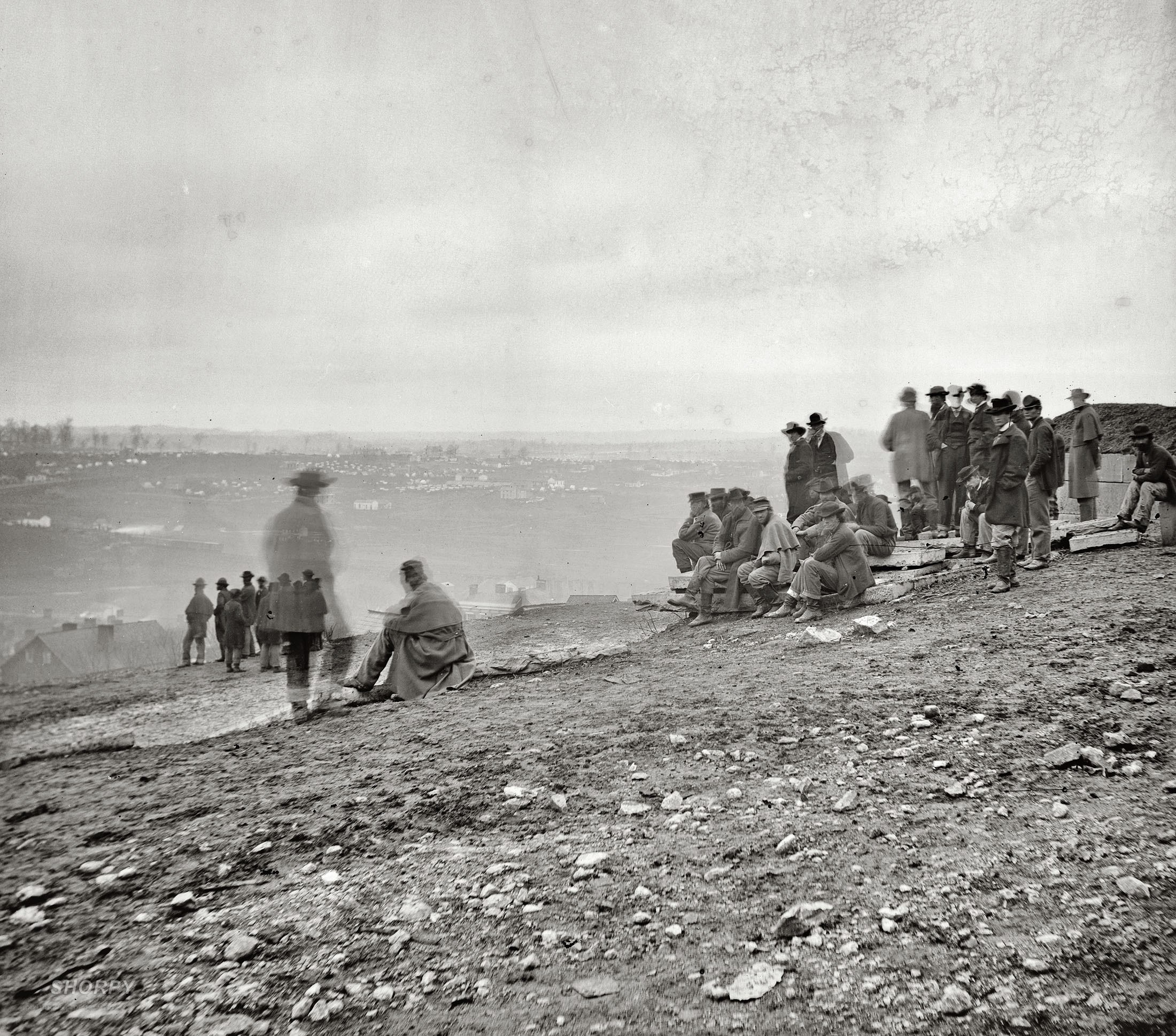 Men on a hillside overlooking a city
