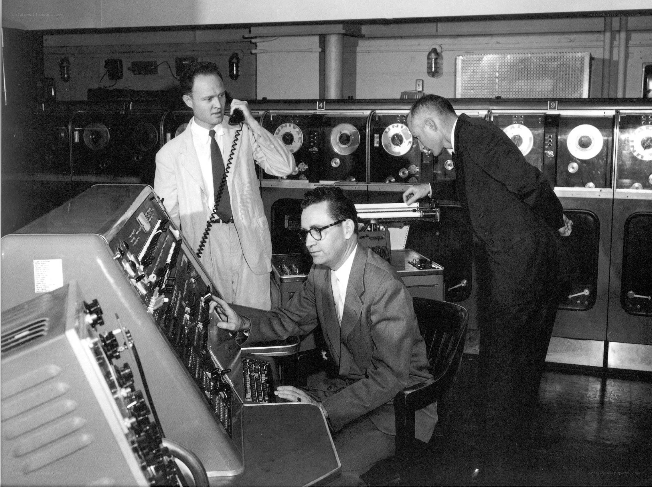Men operating vintage computer equipment