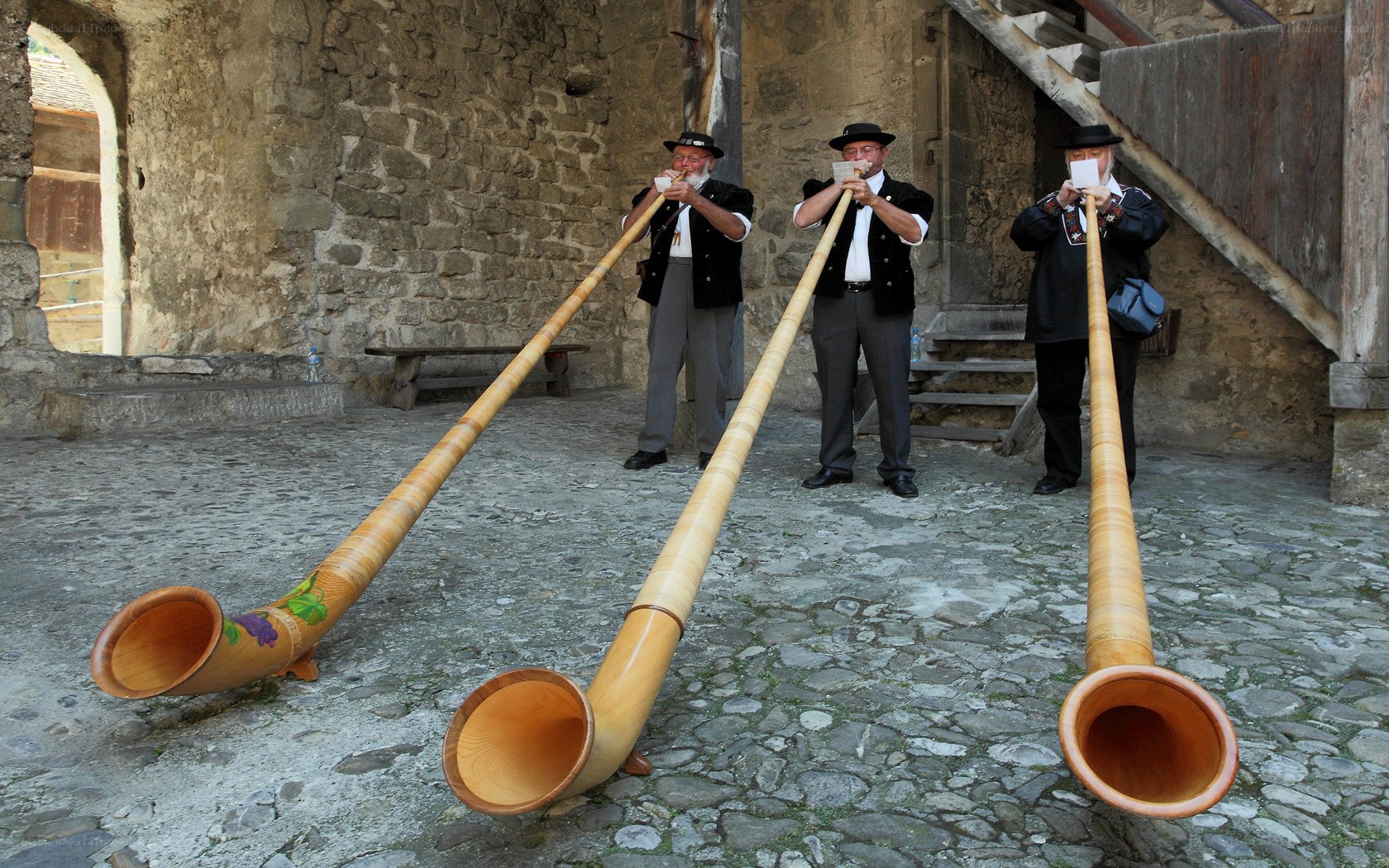 Men playing alphorns in courtyard