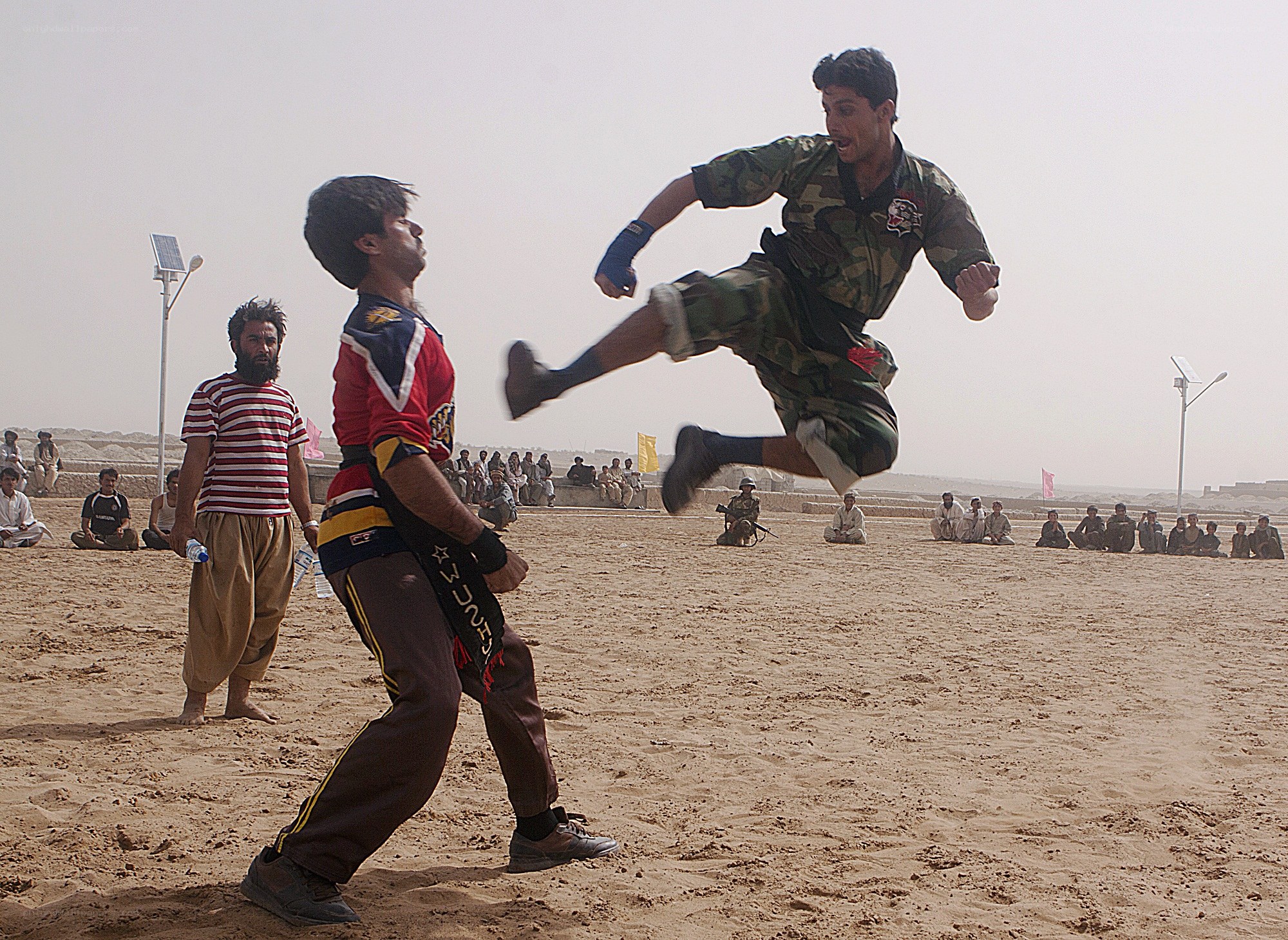 Men practicing martial arts in desert