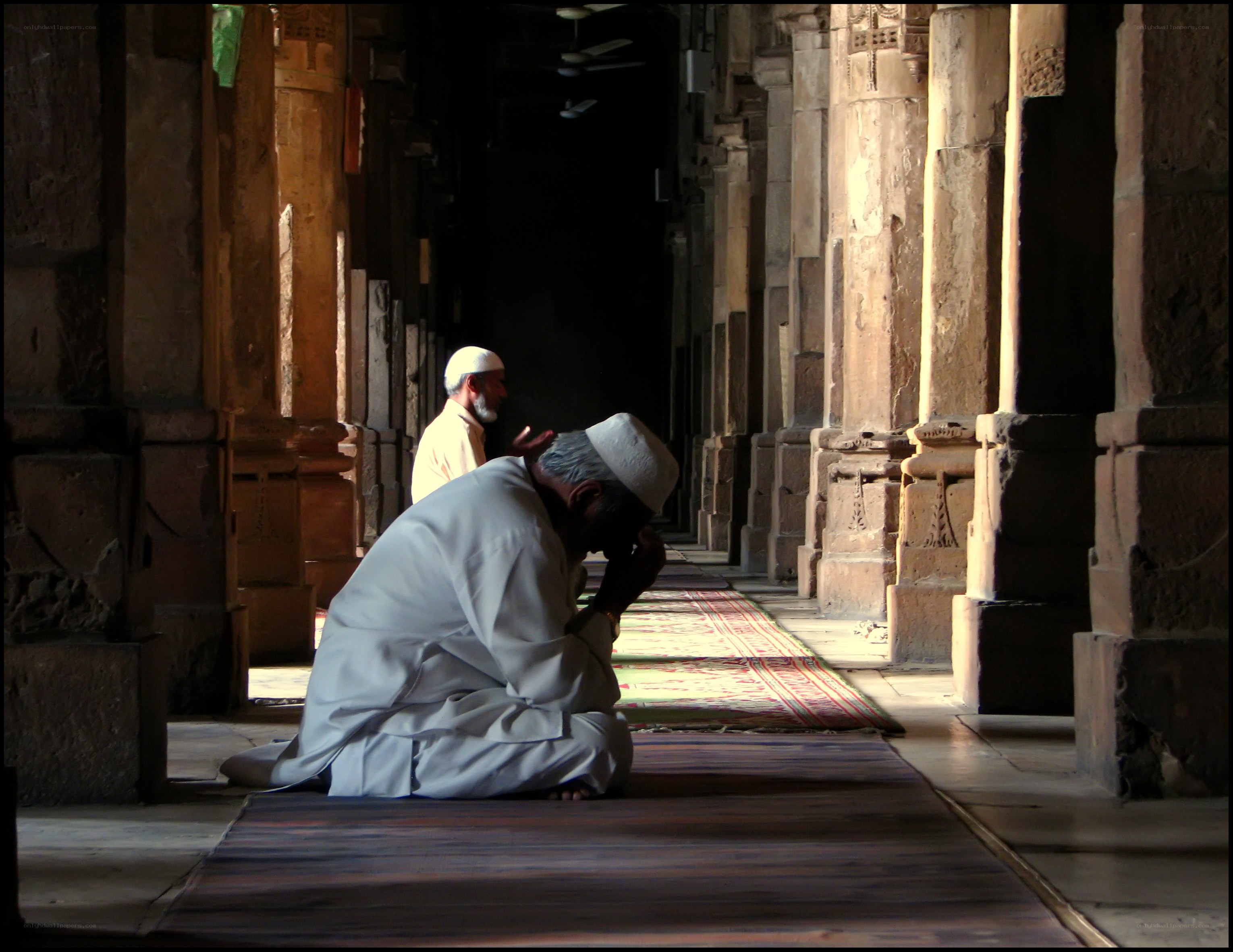 Men praying in a mosque corridor