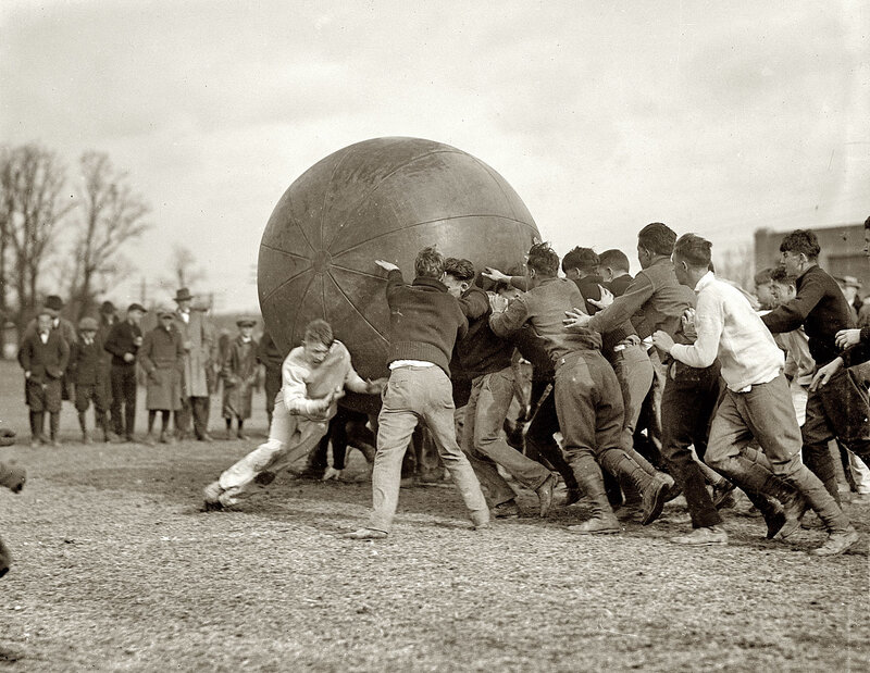 Men pushing large ball