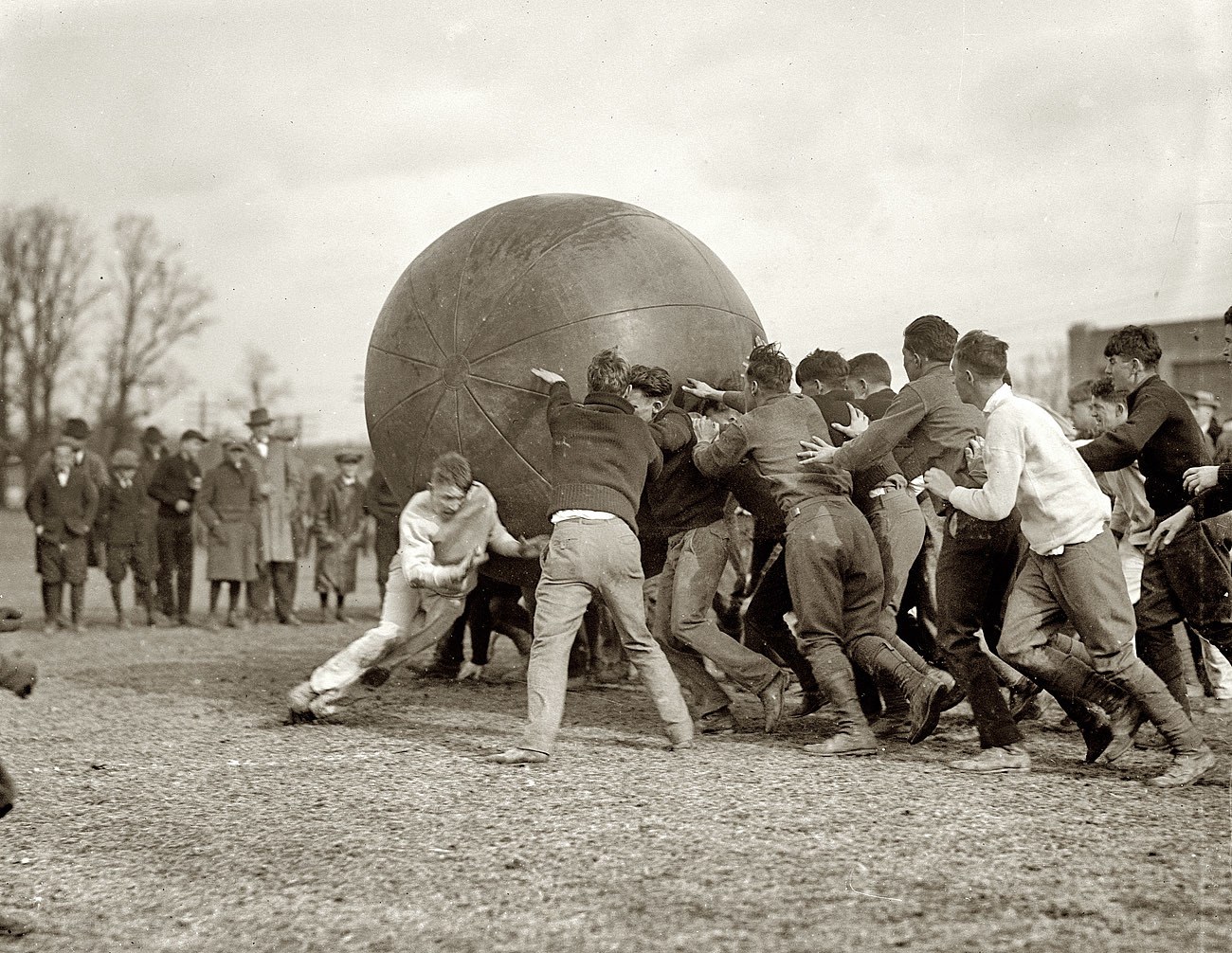 Men pushing large ball