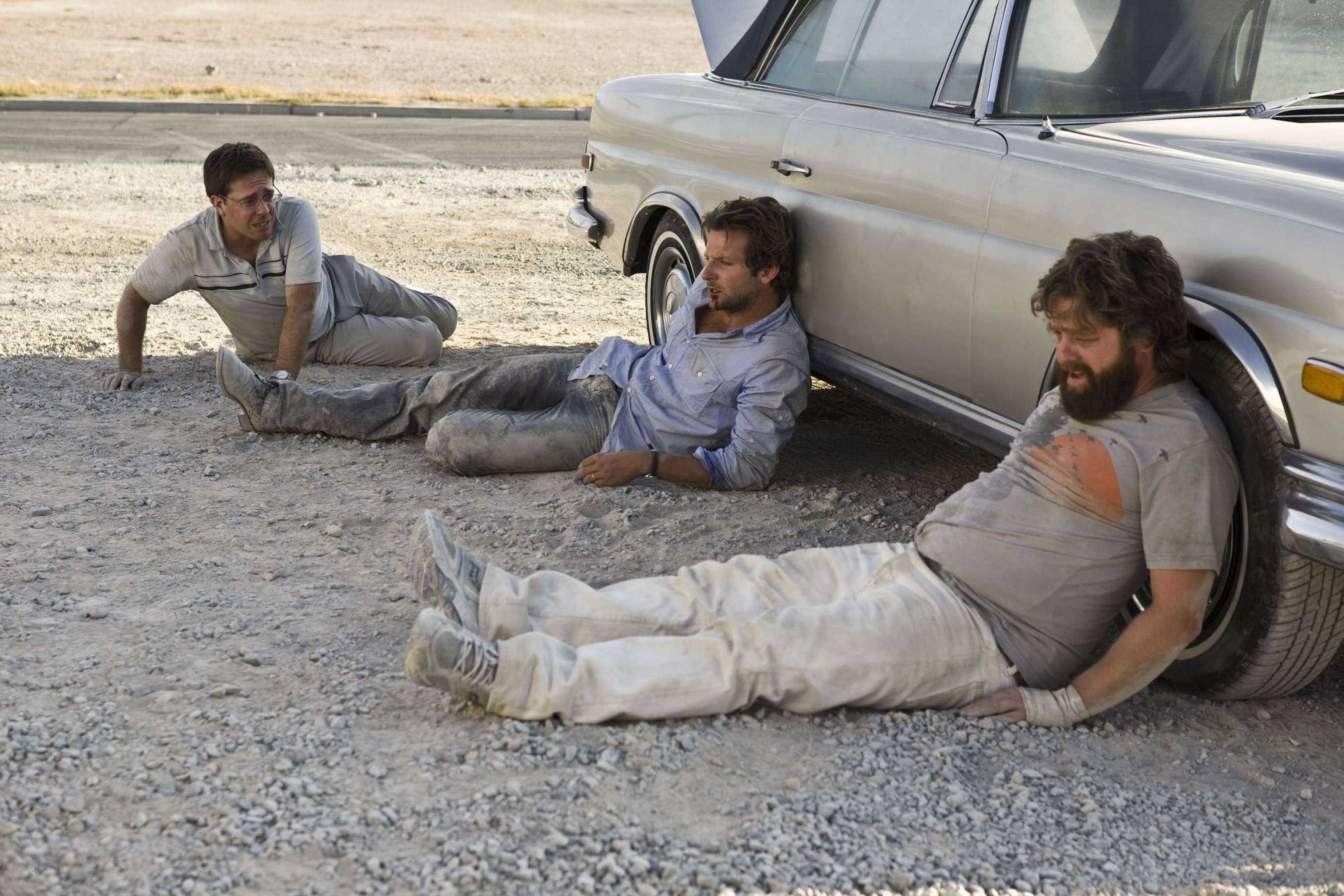 Men resting by car in desert