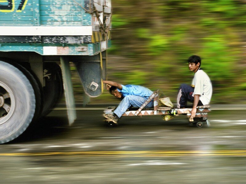 Men riding a cart behind a truck