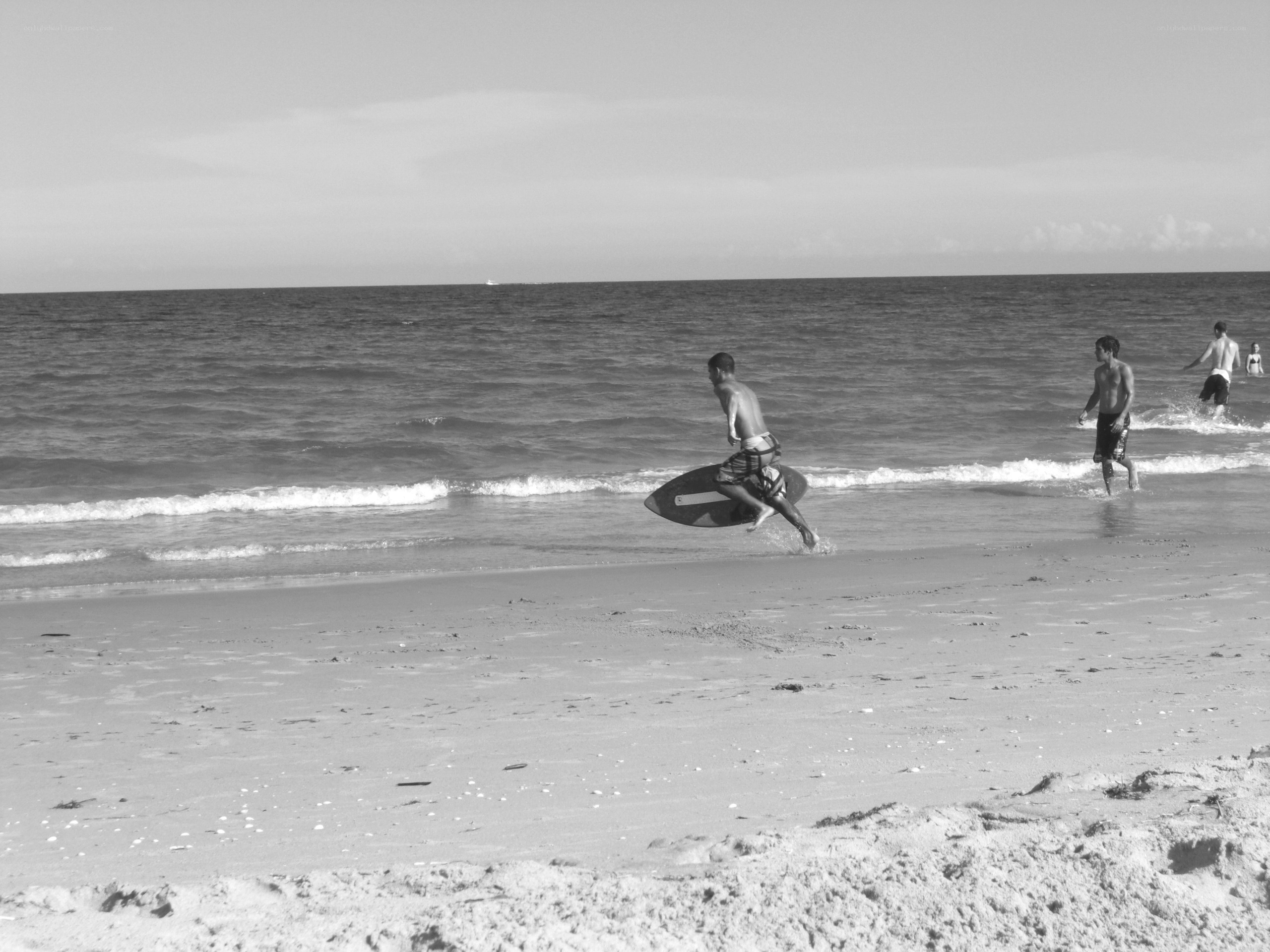 Men running on beach with surfboard