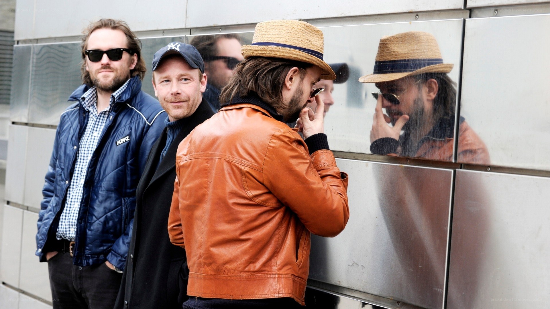 Men standing by a reflective wall