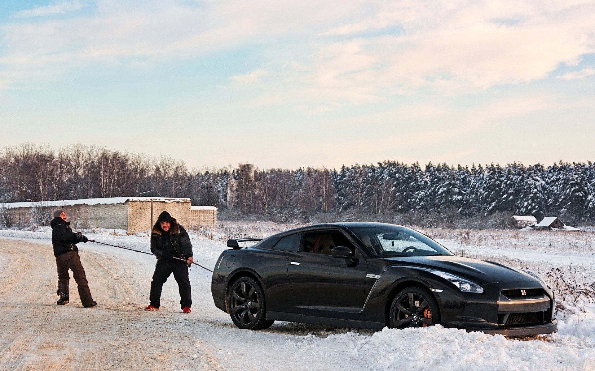 Men towing car in snow
