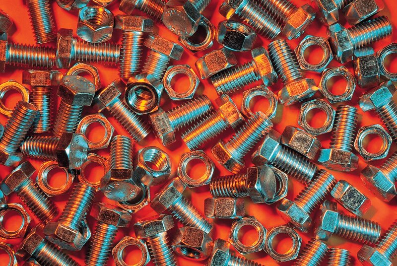 Metal bolts and nuts on red