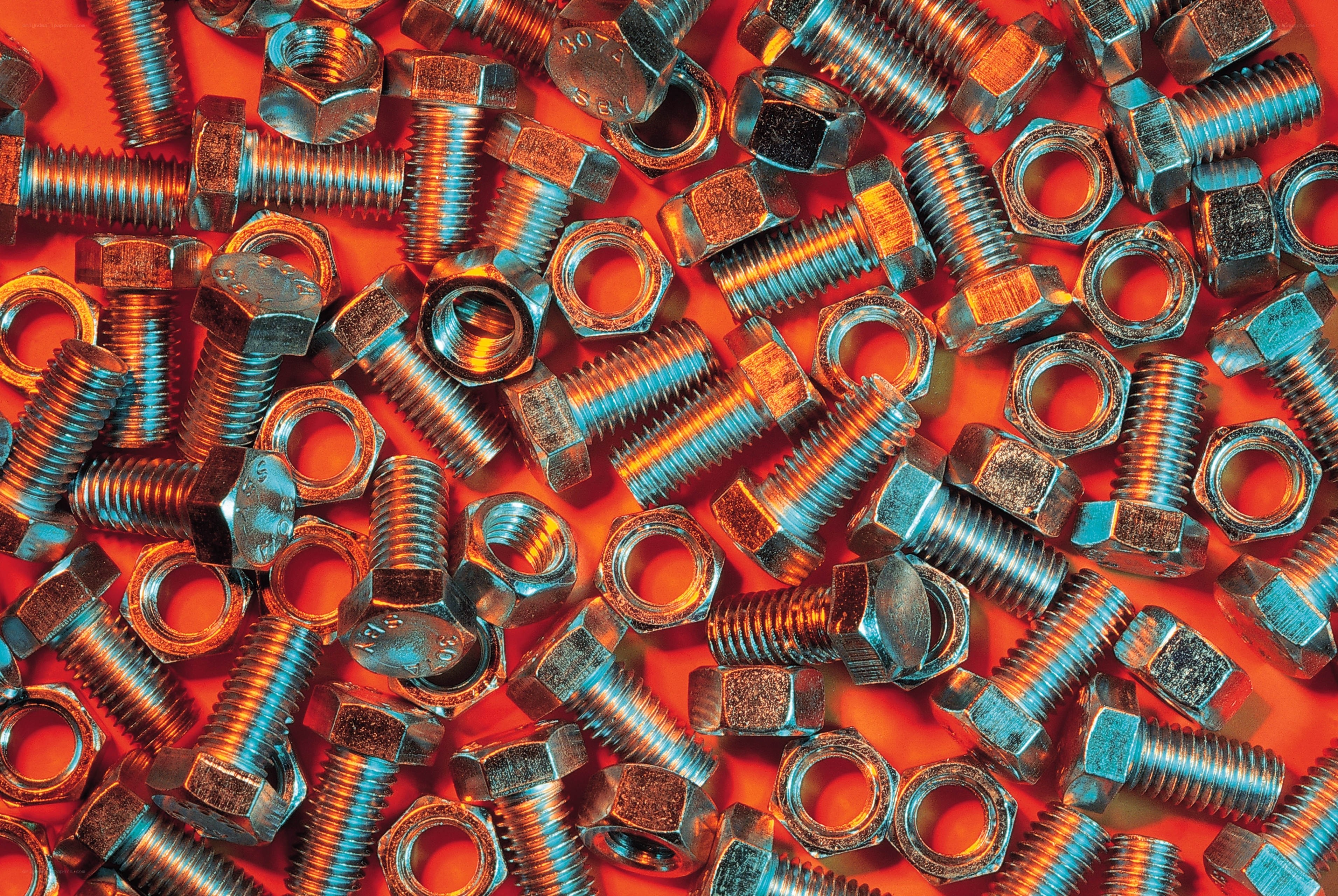 Metal bolts and nuts on red