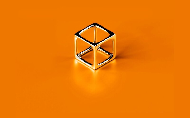 Metallic cube on orange background