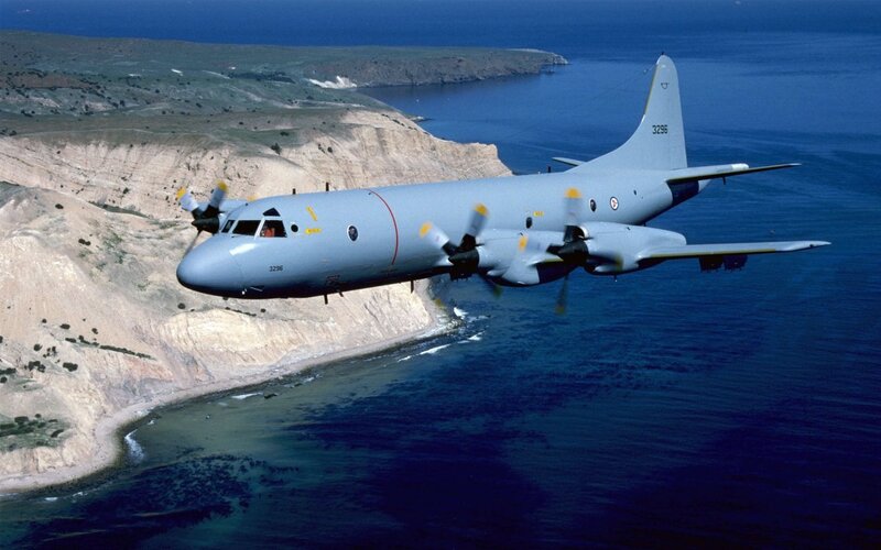 Military aircraft flying over coastline