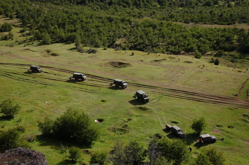 Military convoy in grassy field