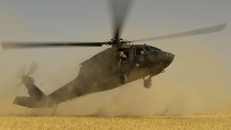 Military helicopter in dusty field