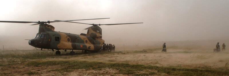 Military helicopter in dusty field