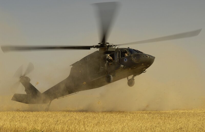 Military helicopter in dusty field