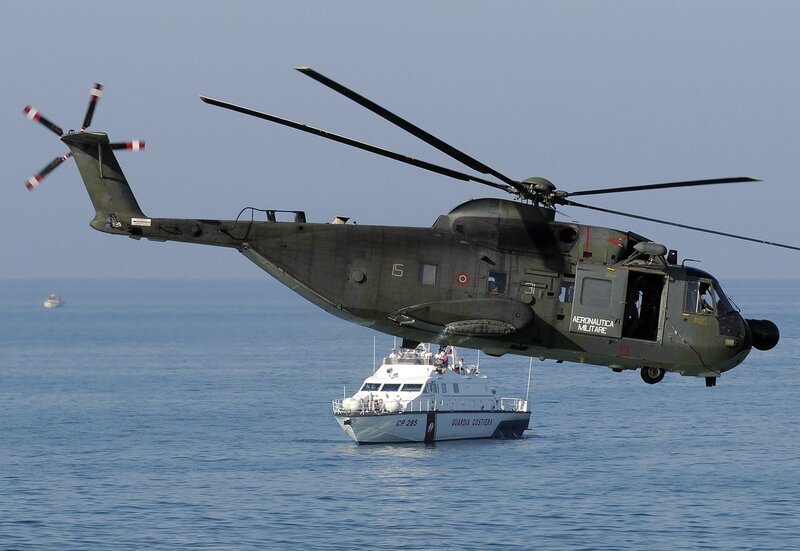 Military helicopter over coast guard boat