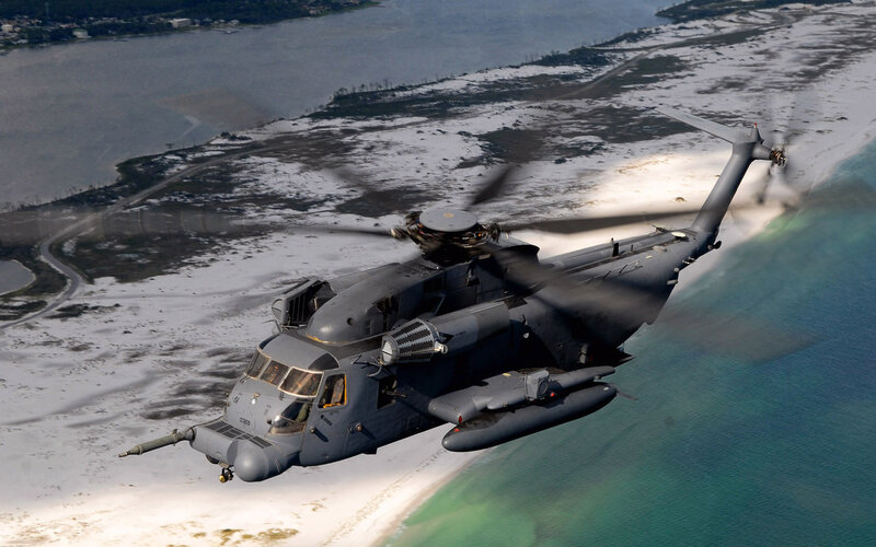 Military helicopter over coastal area