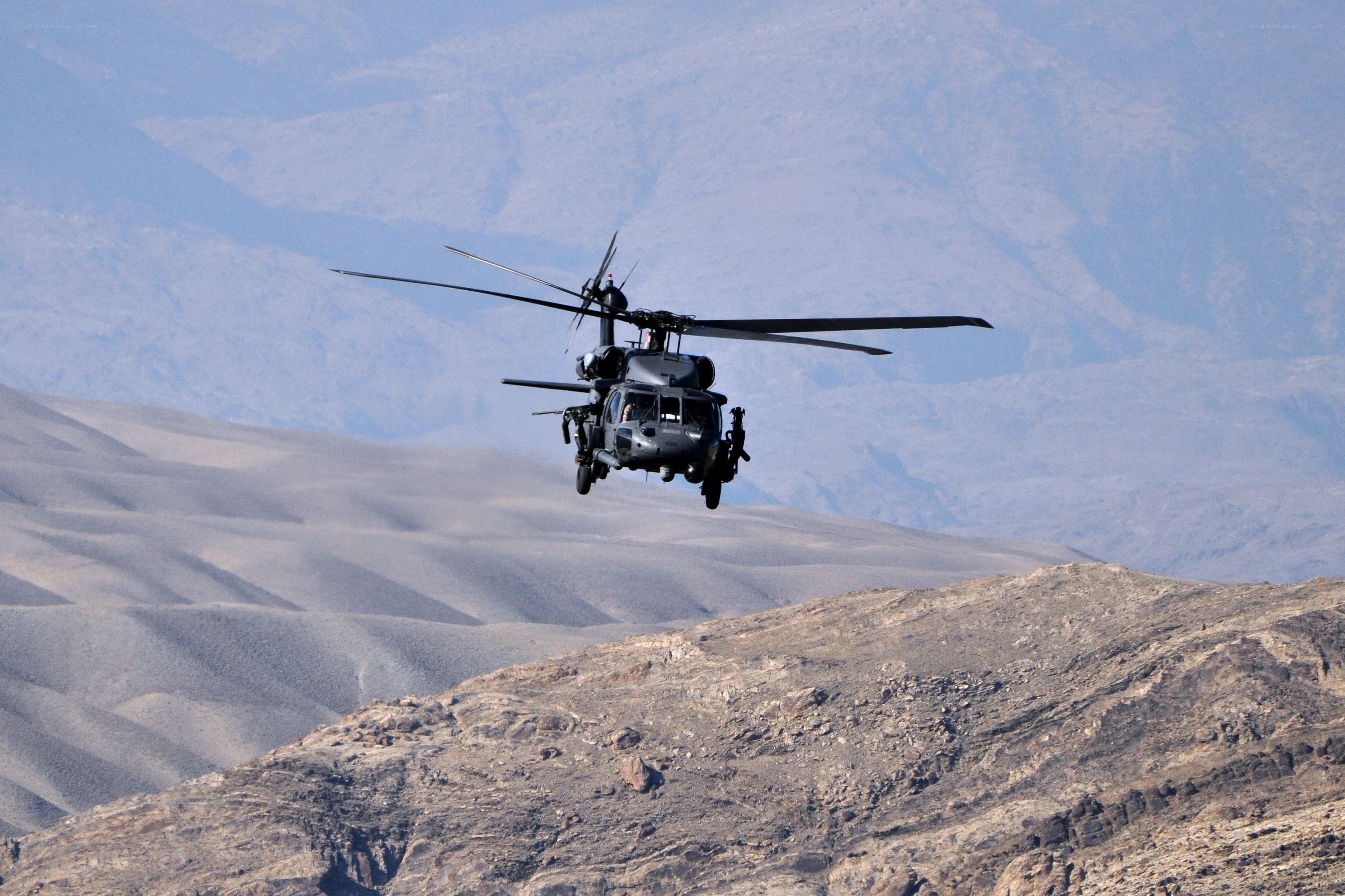 Military helicopter over desert mountains