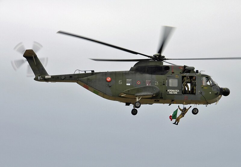 Military helicopter with soldier rappelling