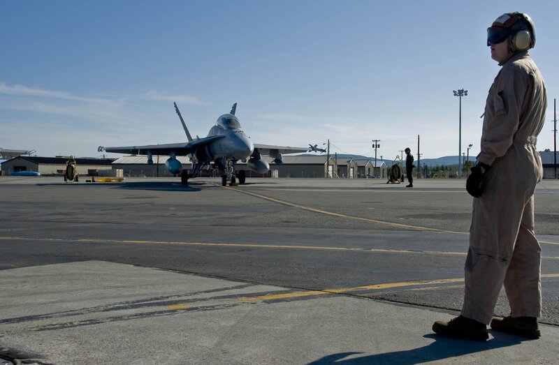 Military jet on tarmac with crew