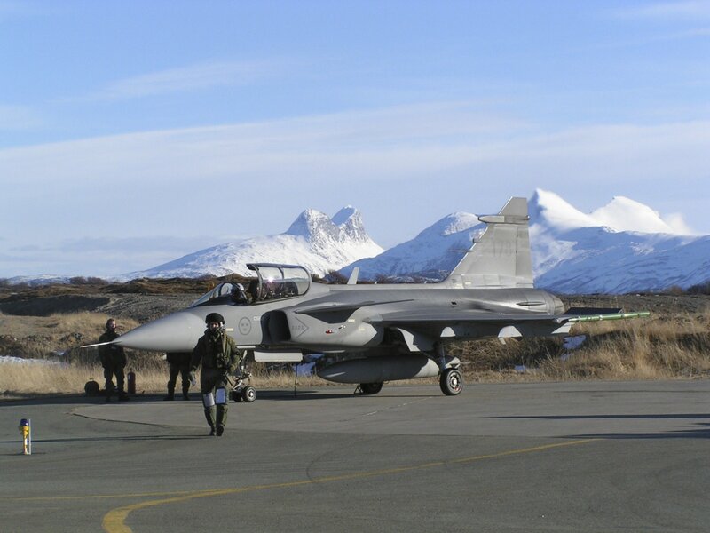 Military jet on tarmac with mountains