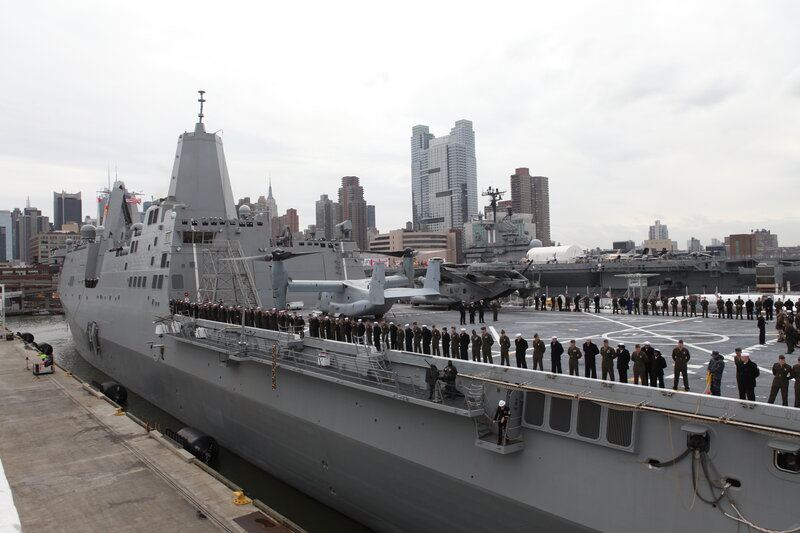 Military ship at dock with city skyline