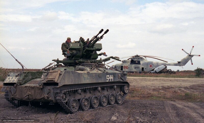 Military tank and helicopter on field