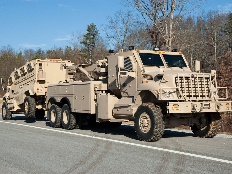 Military truck towing armored vehicle
