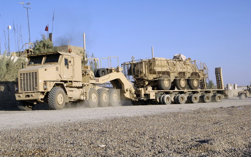 Military truck transporting armored vehicle