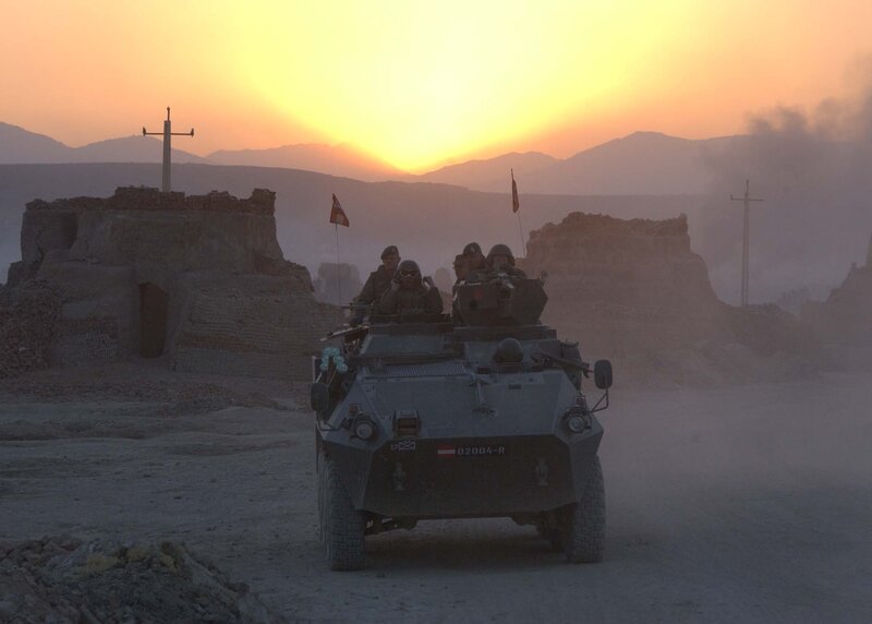 Military vehicle in desert at sunset
