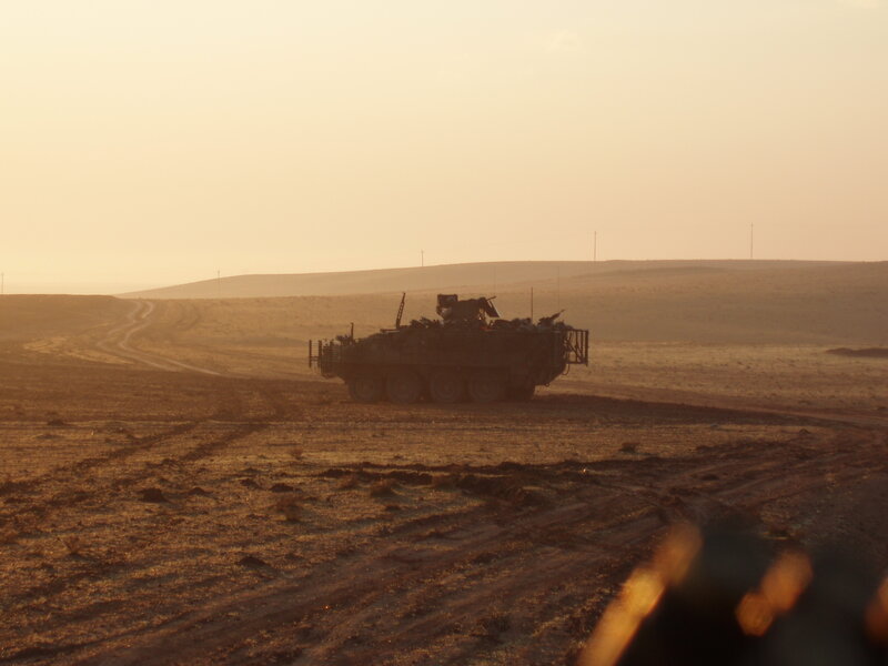 Military vehicle in desert at sunset