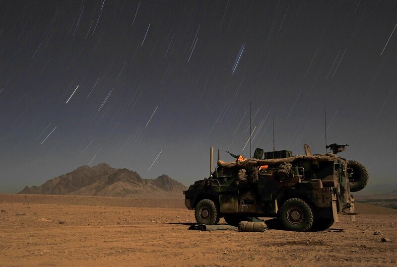Military vehicle under star trails