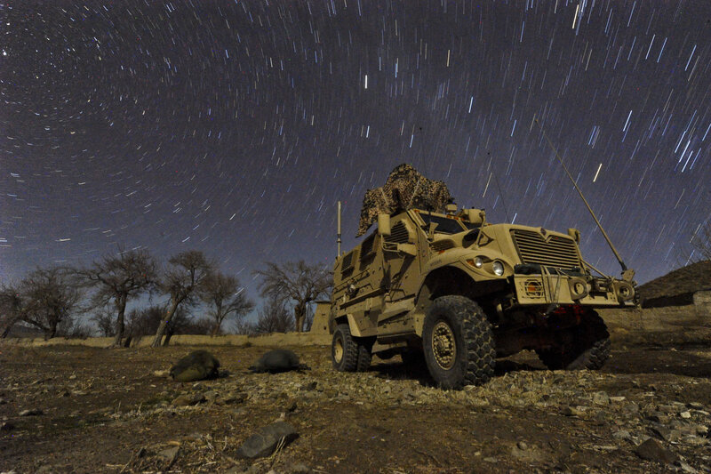 Military vehicle under star trails