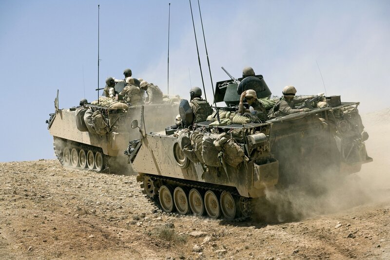 Military vehicles on a dusty hill