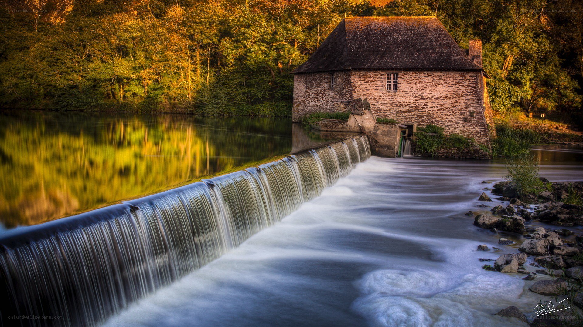 Mill by a waterfall at sunset