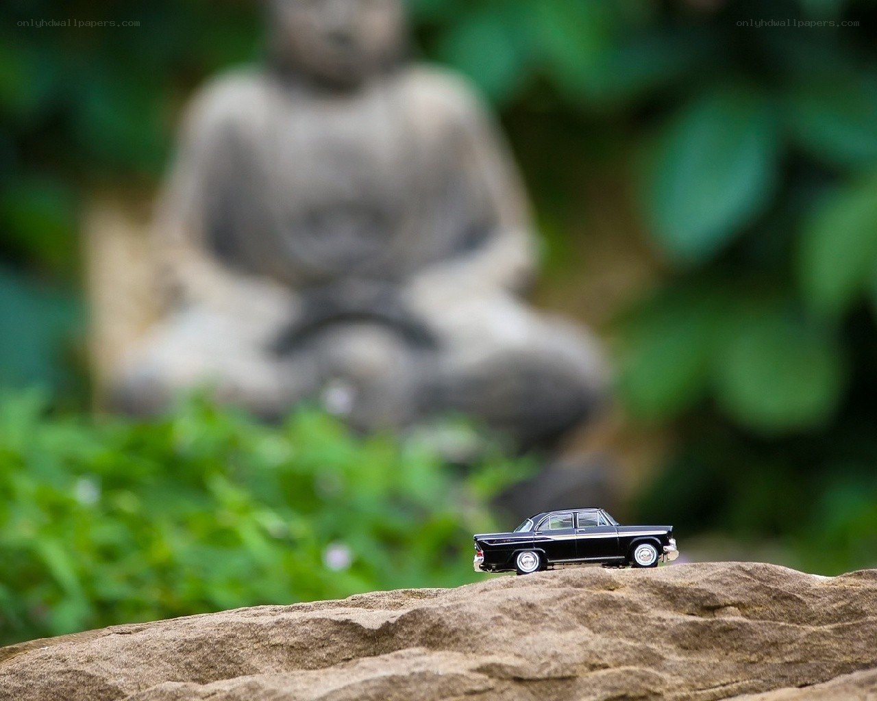Mini car on a rock with statue