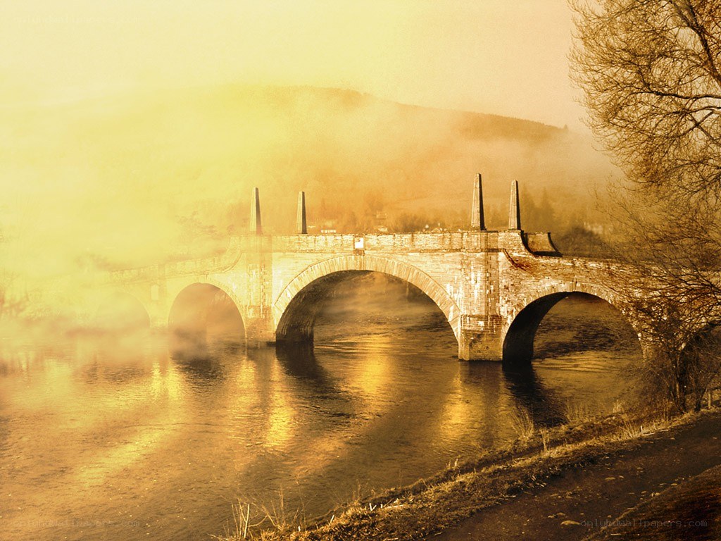 Misty bridge over river at dawn
