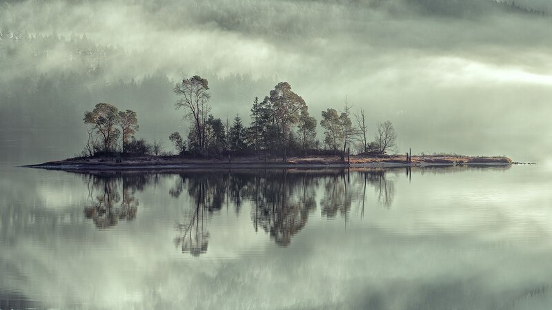 Misty island in calm lake