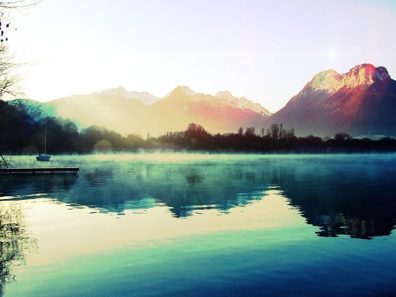 Misty lake at sunrise with mountains