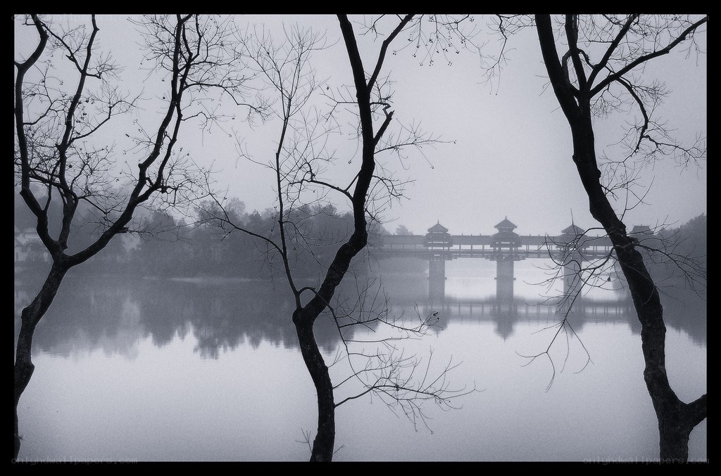 Misty lake with covered bridge