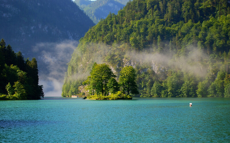 Misty lake with forested mountains