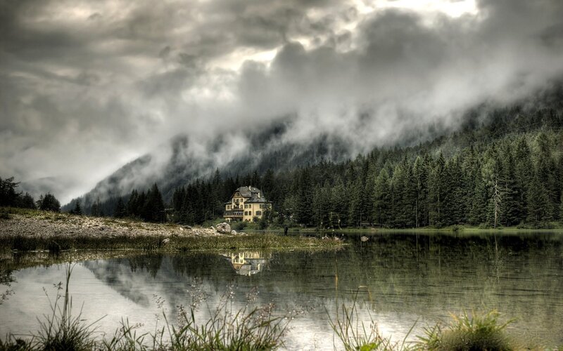 Misty lake with house in forest
