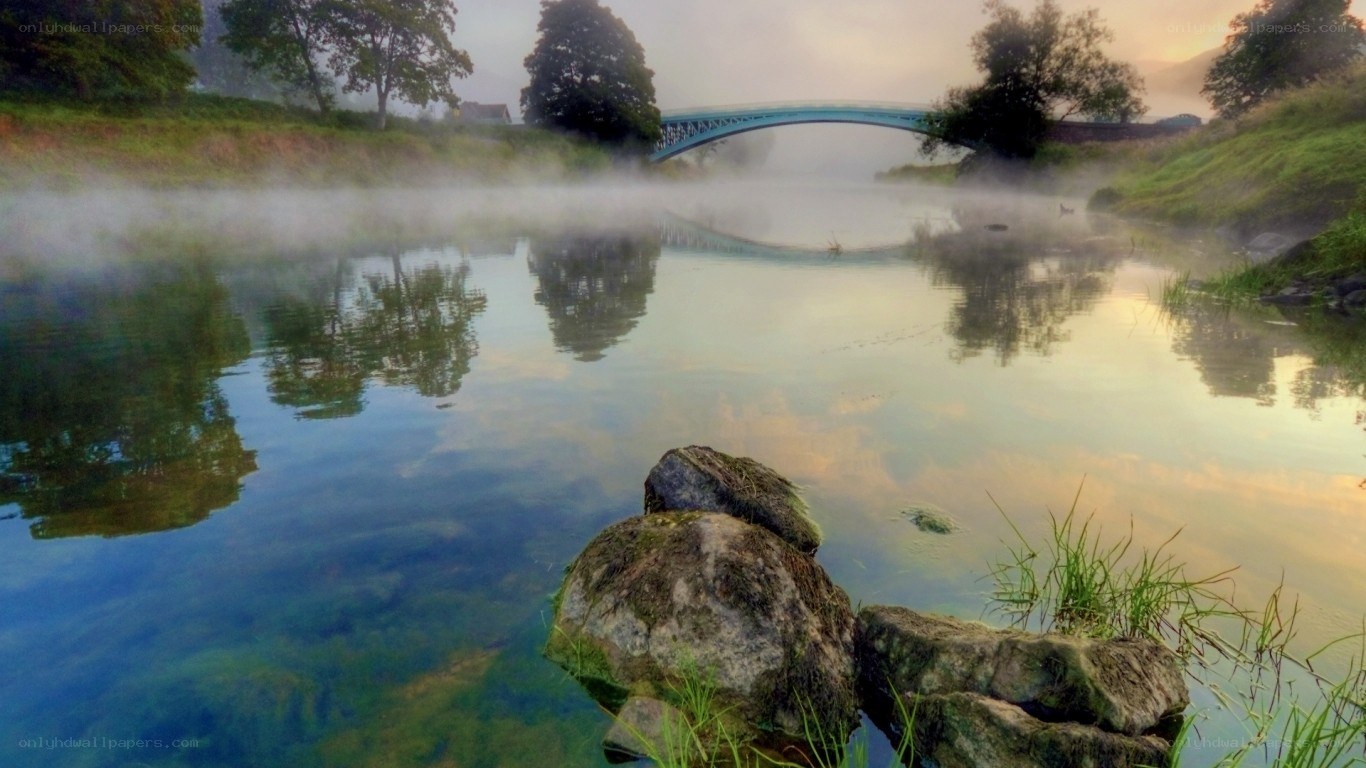 Misty river with bridge at dawn