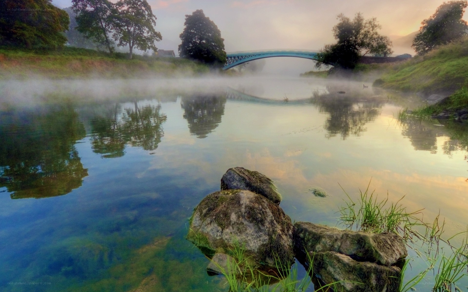 Misty river with bridge at dawn