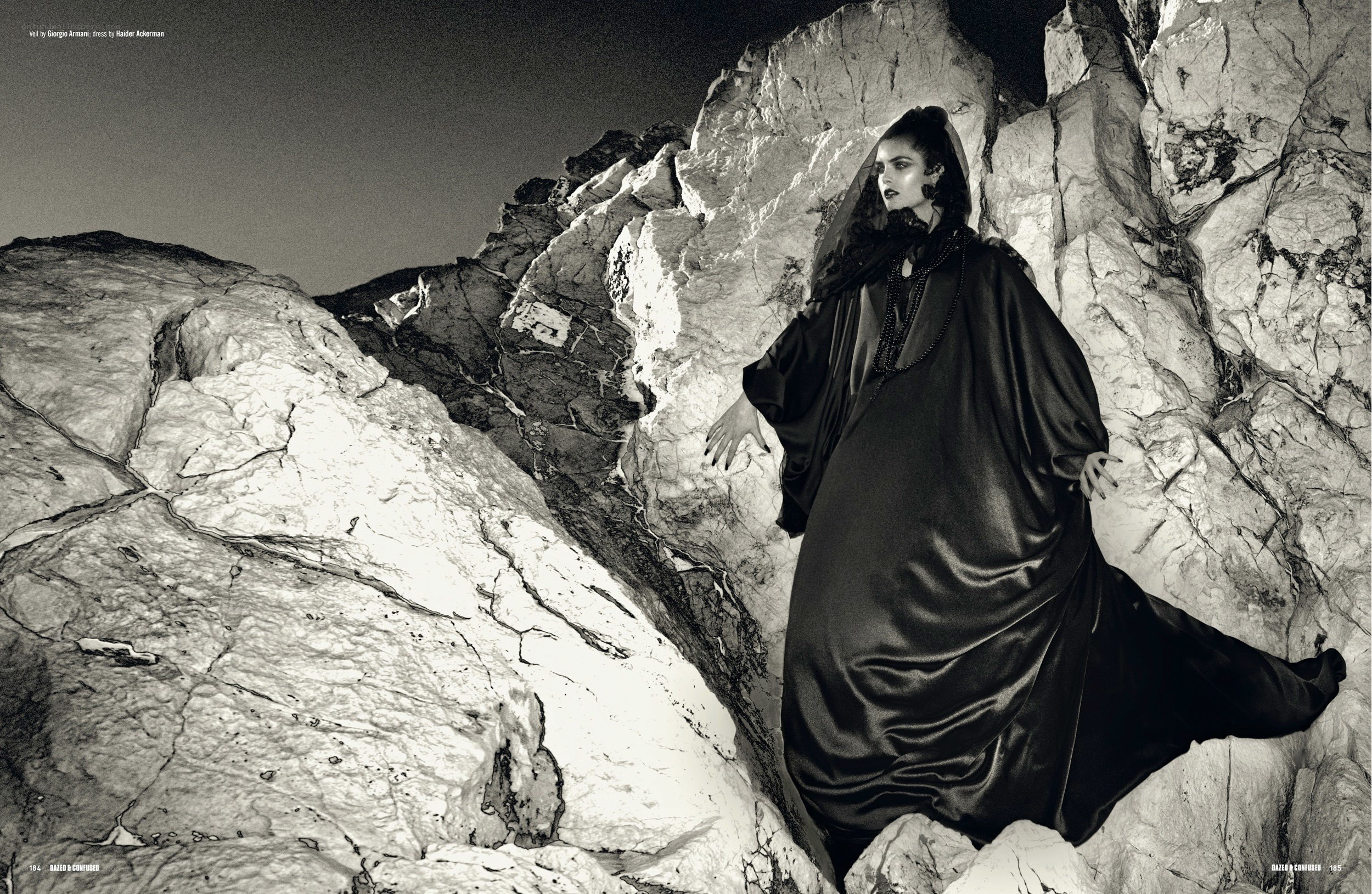 model in black robe on rocks
