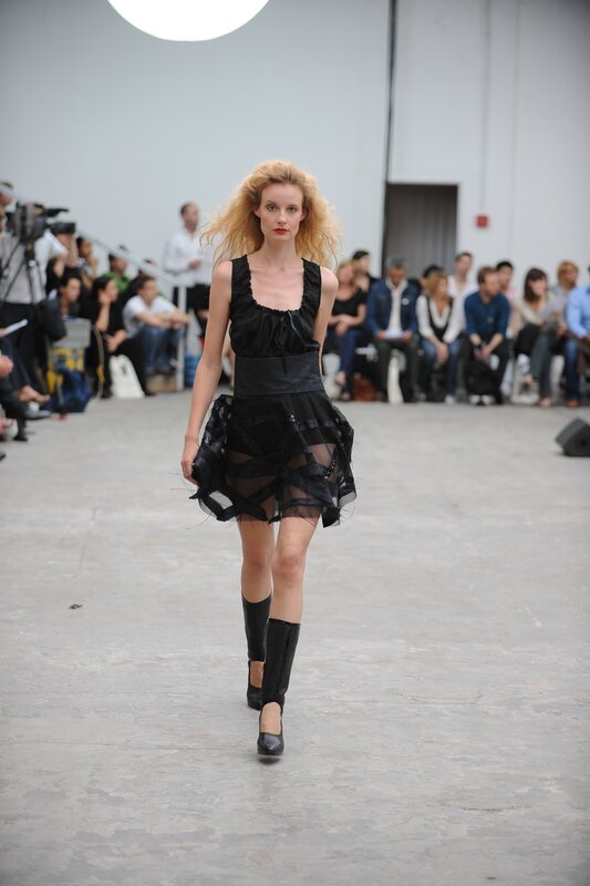Model walks runway in black dress