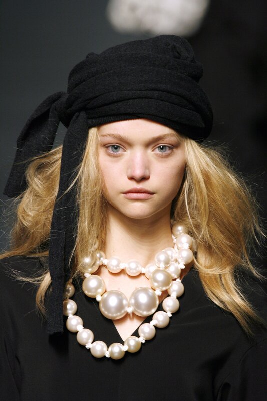 Model with pearl necklace and black hat