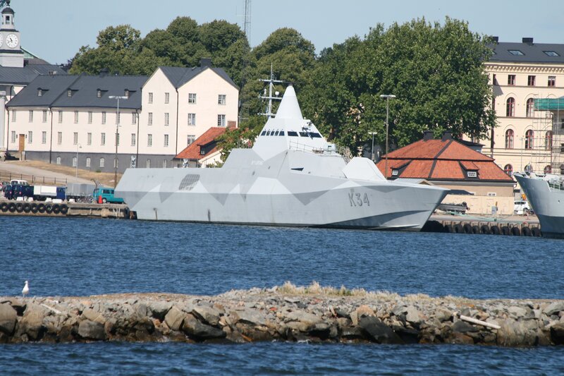 Modern Warship in Harbor — Gray, Calm, Afternoon, Photograph, Buildings